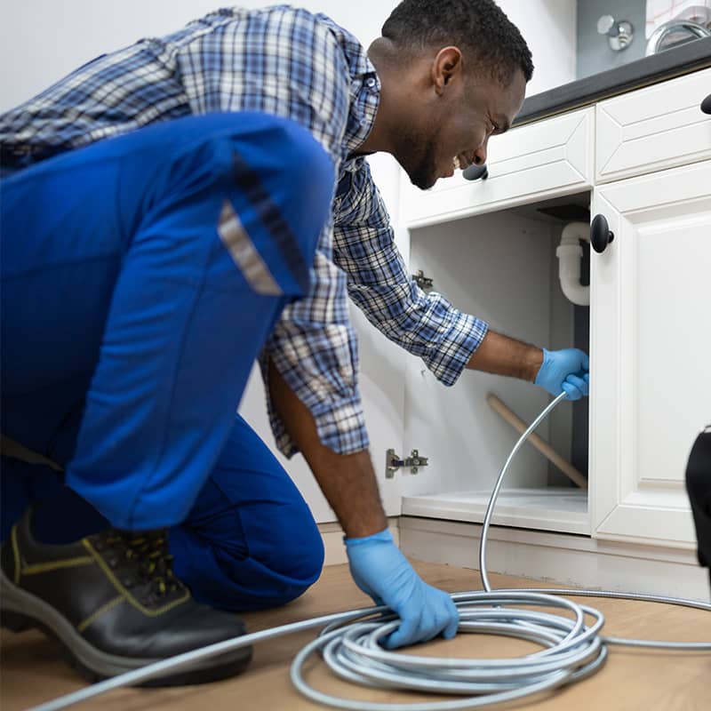 Professional unblocker cleaning a drain, showcasing the difference between plumbing and drainage systems.