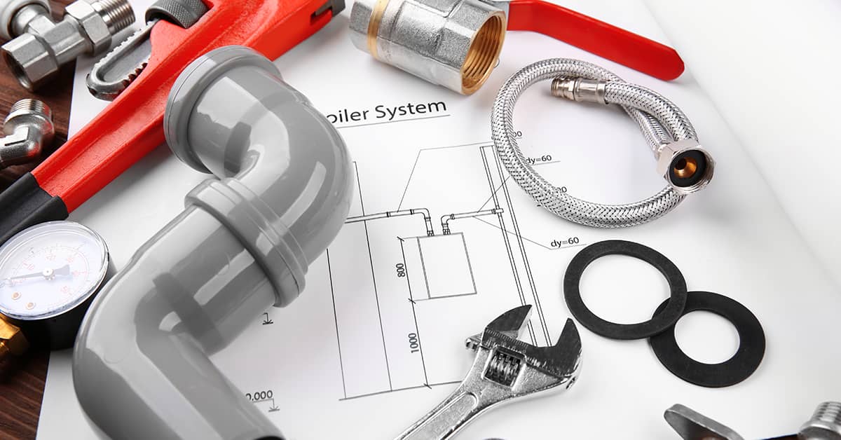 Assortment of plumbing tools laid out next to a detailed house plan.
