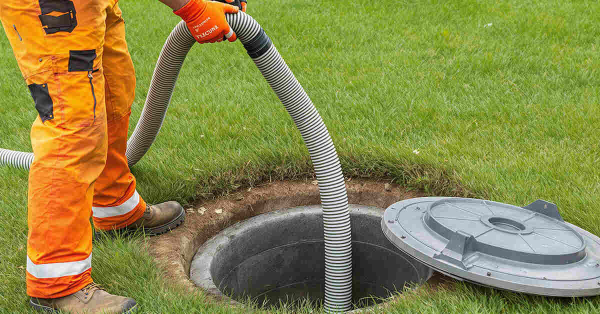 Drainage engineer emptying a septic tank using a vacuum hose.