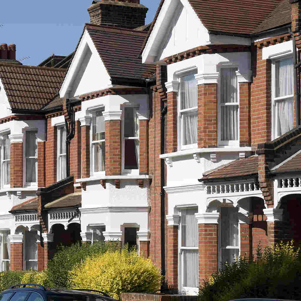 A row of red-brick UK houses with bay windows, emphasizing the need for a drain survey before purchasing a property.